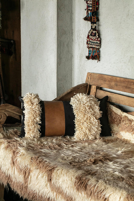 Black Boho Arca decorative pillow cover with cotton tassels and faux leather on bench