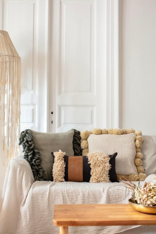 Bohemian rectangle Arca throw pillow with tassels and faux leather on white sofa in cozy living room