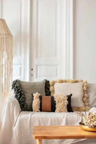 Bohemian rectangle Arca throw pillow with tassels and faux leather on white sofa in cozy living room
