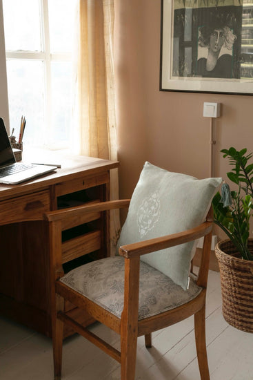 Mint green blockprint cushion cover on wooden chair in cozy home office