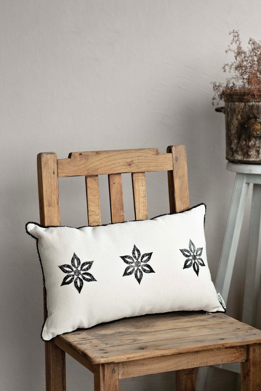 Handmade beige blockprint cushion cover with black star motifs placed on rustic wooden chair