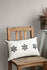 Handmade beige blockprint cushion cover with black star motifs placed on rustic wooden chair