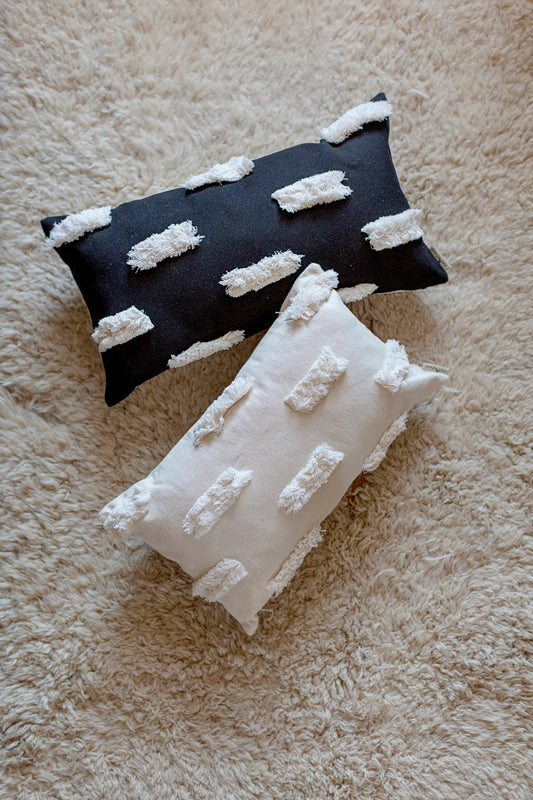 Textured rectangular Bohemian pillow covers in black and ecru on soft beige carpet