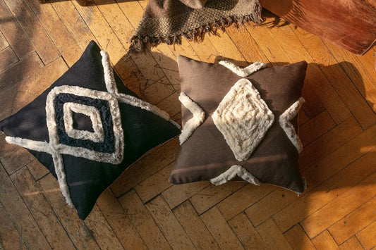 Navy and brown Bohemian decorative pillow covers with hand-stitched diamond patterns on wooden floor