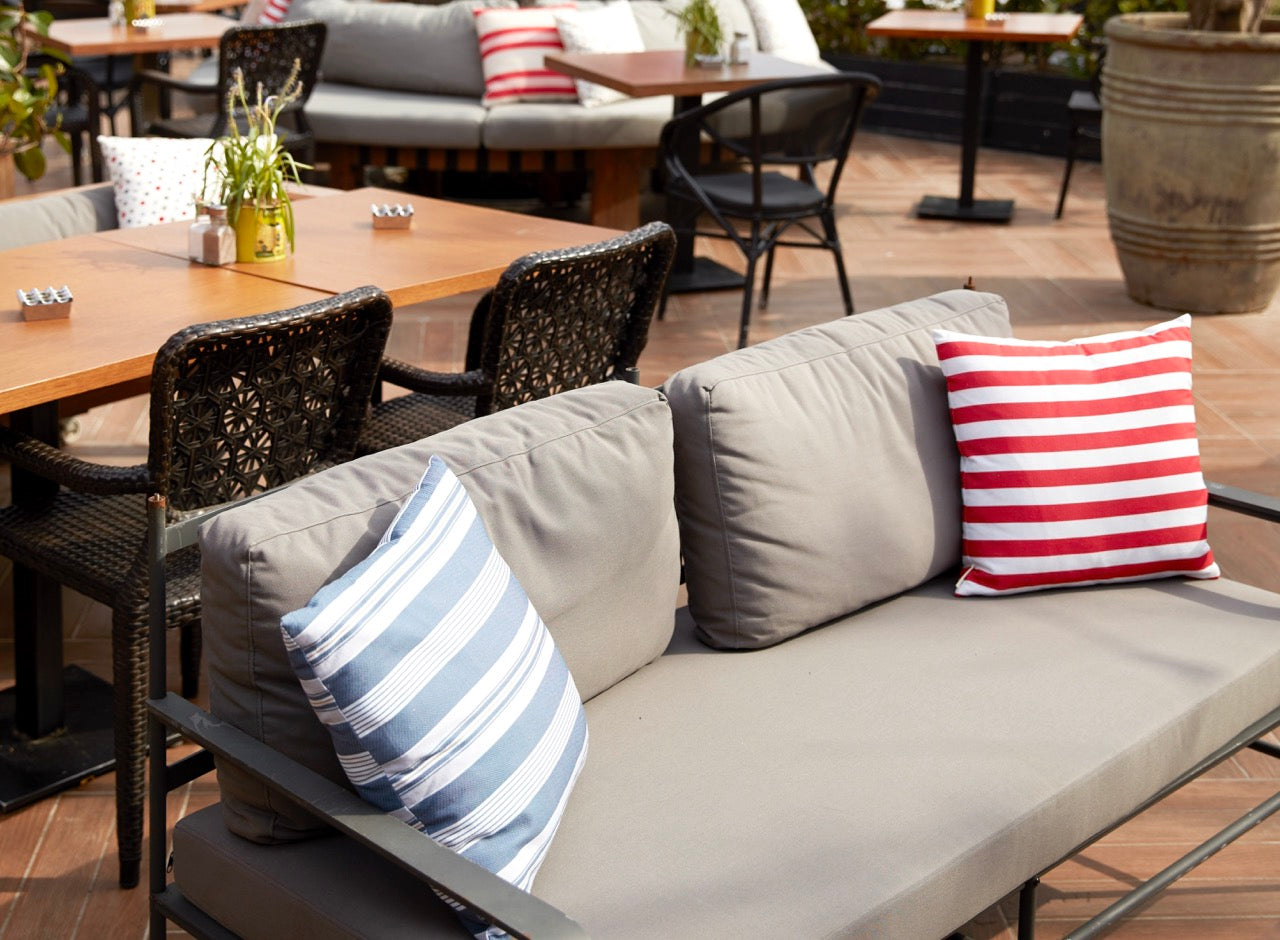 Striped outdoor decorative cushion on grey bench under sun